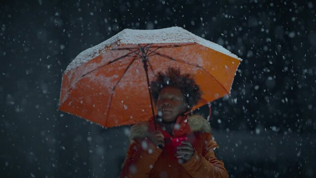 Black Female Person with Curly Hair Holding Candlelight in Snowy Winter Weather