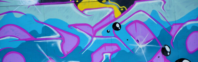 Colorful background of graffiti painting artwork with bright aerosol outlines on wall. Old school street art piece made with aerosol spray paint cans. Contemporary youth culture backdrop