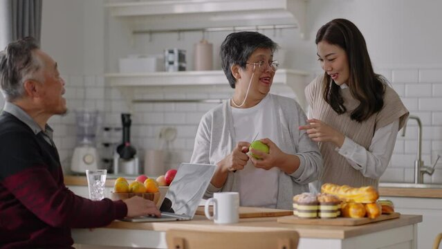 Happy mature old couple of parents and daughter cooking family dinner in kitchen,Mother teaching daughter to peel fruit,enjoying leisure,holiday,culinary hobby,active enjoy family retirement weekend.