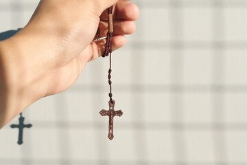 Male hand holding holy rosary with shadow. Christianity, faith and praying concept.