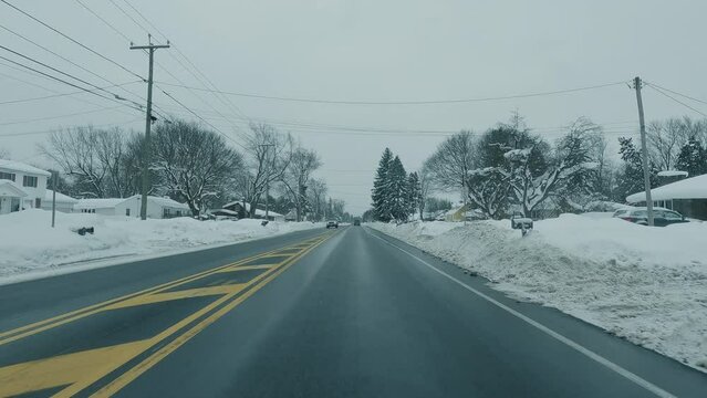 Driving down a snow-covered suburban road during the middle of winter.