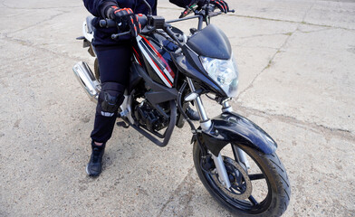 woman motorcyclist in a helmet, motorcycle gloves, motorcycle boots on a motorcycle close-up