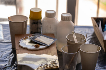mesa de trabajo con materiales para trabajar resina epóxica, tabla de cocina, porta vaso y vasos...