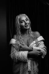 Portrait of a young girl with blond hair in a dressing gown in a low key.