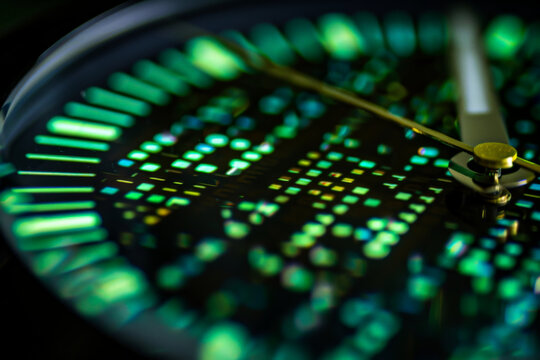 A close up of a watch face with green numbers