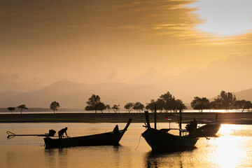 Long tail boat on tropical beach, under cloudy sky