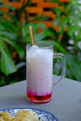 Iced Rose Milk in glass on the table. Fresh and cold drink. Milk and rose syrup with ice