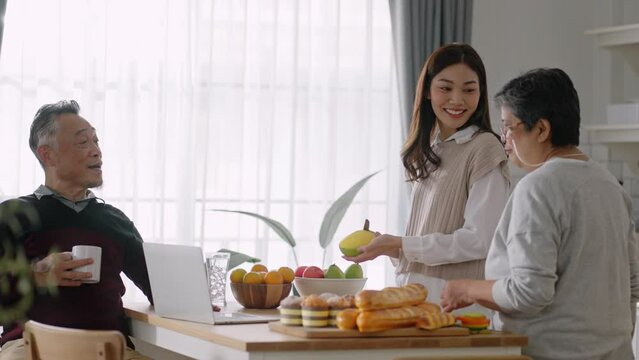 Happy mature old couple of parents and daughter cooking family dinner in kitchen,Mother teaching daughter to peel fruit,enjoying leisure,holiday,culinary hobby,active enjoy family retirement weekend.