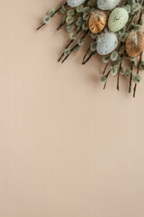 flat lay photo of fluffy willow branches and Easter eggs in pastel shades on a beige background. an Easter card. free space for text.