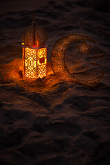 Ramadan lantern with crescent moon on the beach sand, 2024 Eid Mubarak and Ramadan Kareem greeting...