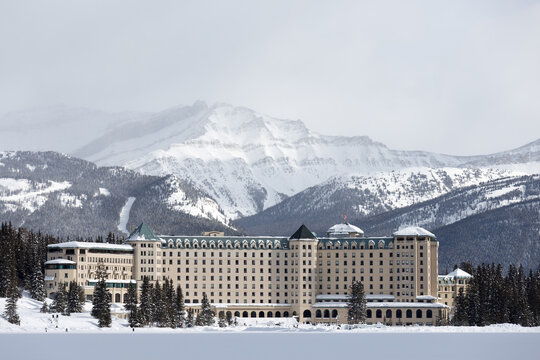 Chateau Lake Louise hotel in front of half frozen lake Louise - Banff , Alberta, Canada.