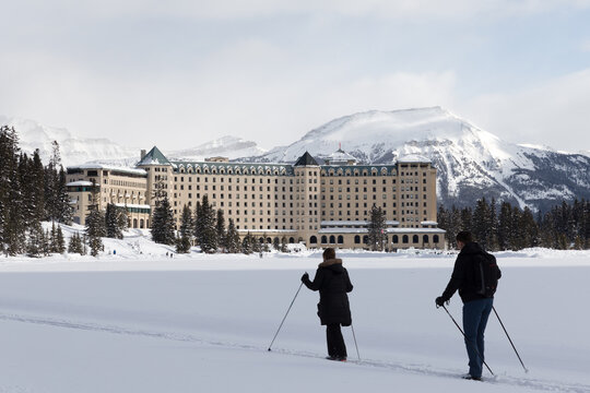 Chateau Lake Louise hotel in front of half frozen lake Louise - Banff , Alberta, Canada.