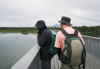 Tourists on the bridge over Brooks river, watching salmon swimming under the bridge. Katmai National Park. Alaska.