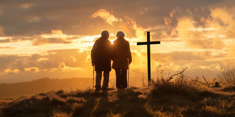 Silhouette of senior couple on high hill with cross during sunrise or sunset. Regretting sins, missing people who passed away, deeply religious person, praying, thinking about soul and meaning of life - obrazy, fototapety, plakaty
