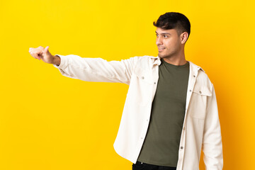 Young Colombian man isolated on yellow background giving a thumbs up gesture