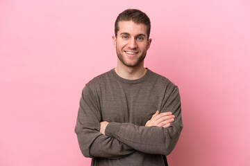Young caucasian man isolated on pink background keeping the arms crossed in frontal position