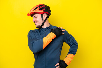 Young cyclist caucasian man isolated on yellow background suffering from pain in shoulder for having made an effort