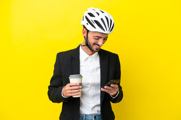 Business caucasian man with a bike helmet isolated on yellow background holding coffee to take away...