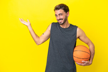 Handsome young basketball player man isolated on yellow background extending hands to the side for...