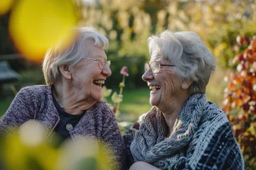 Poster Zwei Rentnerinnen lachen zusammen, sie sitzen im Garten  © Herzog