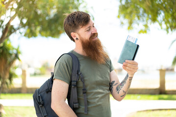 Redhead man with beard holding a passport at outdoors