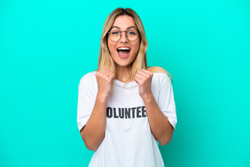 Young volunteer Uruguayan woman isolated on blue background celebrating a victory in winner position