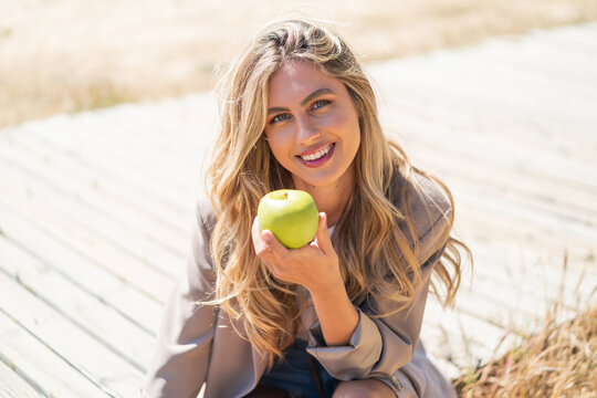 Young pretty blonde Uruguayan woman at outdoors holding an apple