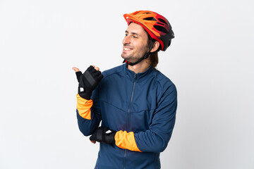 Young cyclist man isolated on white background pointing to the side to present a product - obrazy, fototapety, plakaty