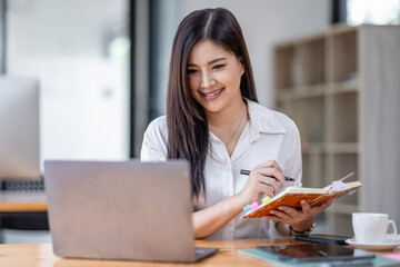 Asian Businesswoman Using laptop computer and working at office with calculator document on desk, doing planning analyzing the financial report, business plan investment, finance analysis concept.
