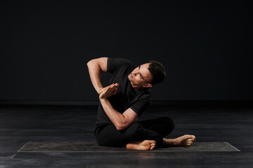 Fototapeta na wymiar The attractive male yogi, donning sleek black garments, exudes a sense of serenity and strength as he deeply connects with his inner self through a series of intricate poses.