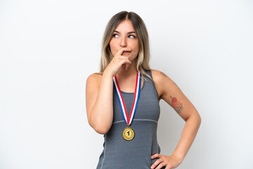 Young Rumanian woman with medals isolated on white background having doubts and with confuse face...