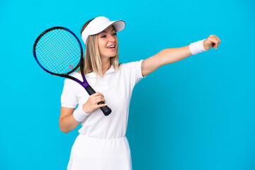 Young tennis player Romanian woman isolated on blue background giving a thumbs up gesture