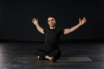  In his striking black attire, the alluring man practices yoga with a mesmerizing fluidity, each posture a work of art in motion on his mat.