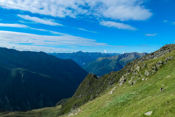 Fototapeta na wymiar Lush green alpine meadow with panoramic view of majestic mountain peaks of High Tauern National Park, Carinthia, Austria. Wanderlust in Austrian Alps. Idyllic high altitude hiking trails in summer