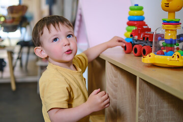 Baby boy playing in the playroom with toys. Kid aged two years