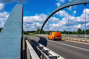 Orange truck driving over bridge