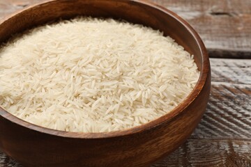 Fototapeta na wymiar Raw basmati rice in bowl on wooden table, closeup