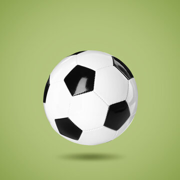 One soccer ball in air on light green background