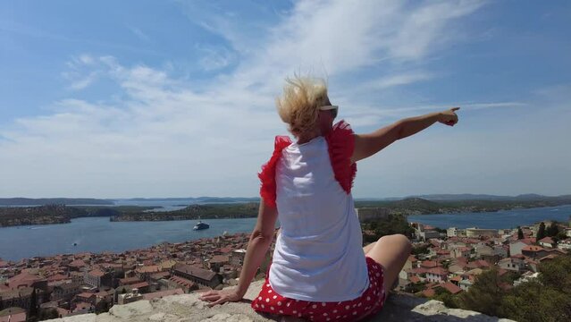 Woman looking the St. John's Fort from the Barone Fortress looking at the cityscape of Sibenik. Skyline with St. Michael castle. Sibenik historic city of Croatia in Dalmatia.