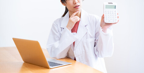 電卓を持ち悩む女性医師
