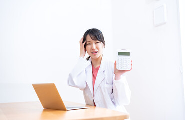 電卓を持ち悩む女性医師
