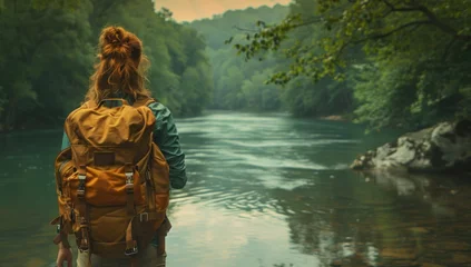 Papier Peint photo Olive verte Adventurous female traveler with backpack standing on cliff overlooking river captivating landscape that blends beauty of nature with spirit perfect for showcasing outdoor travel and hiking