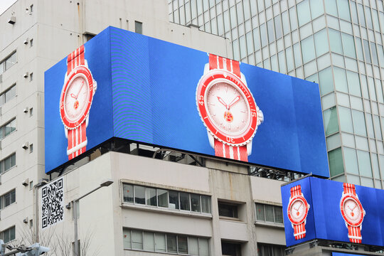 TOKYO, JAPAN - February 17, 2024: A multi-screen billboard with an advert for a Swatch Scuba watch on a building in Tokyo's Omotesando area.