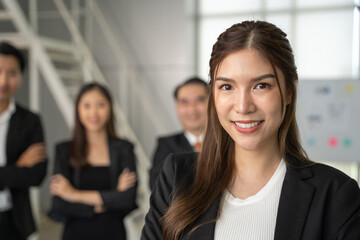 Portrait of young beautiful woman looking to camera in meeting room. She looking to camera with happy expression in her office with team. Business people concept.