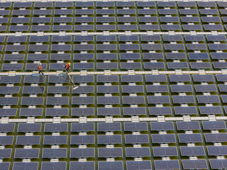 Obraz premium Worker Cleaning floating solar panels or solar cell Platform system on the lake with brush and water. Worker cleaning solar modules in a Solar Energy Power Plant