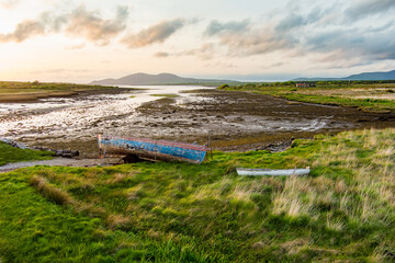 Old boat left on a beach along the Ring of Kerry route. Rugged coast of on Iveragh Peninsula on...