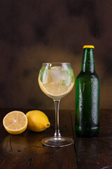 Cocktail in a wine glass. A glass of drink and a bottle nearby. Lemon slices and mint in a glass.