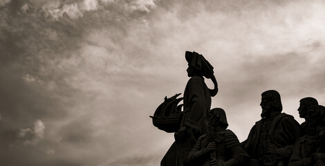 Backlit silhouettes of limestone sculptures and Henry the Navigator holding in his hand a ship from...