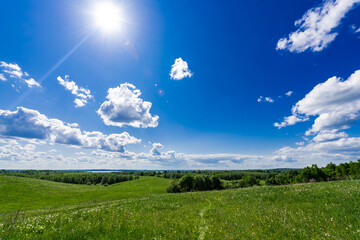 Beautiful landscape of field, forest, lake and blue sky