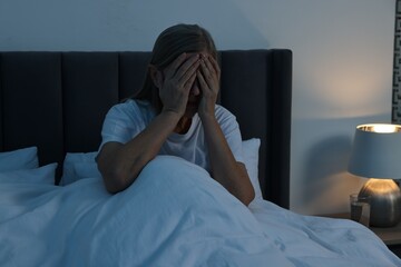 Woman suffering from headache in bed at night